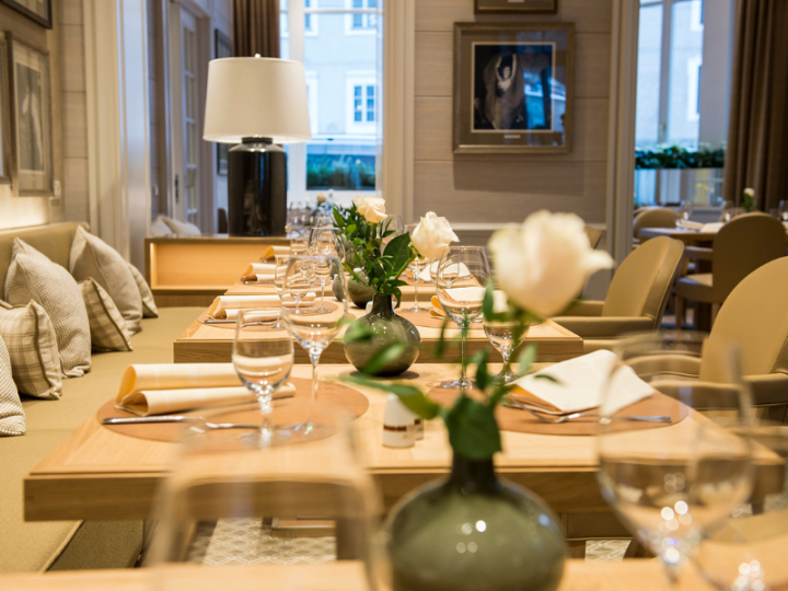 Elegantly set table with white roses at the restaurant of Hotel Sacher Salzburg.
