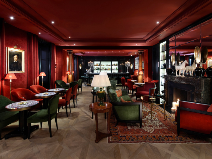 Stilvolle Sacher Bar mit roten und grünen Samtsesseln und Kamin im Hotel Sacher Salzburg.